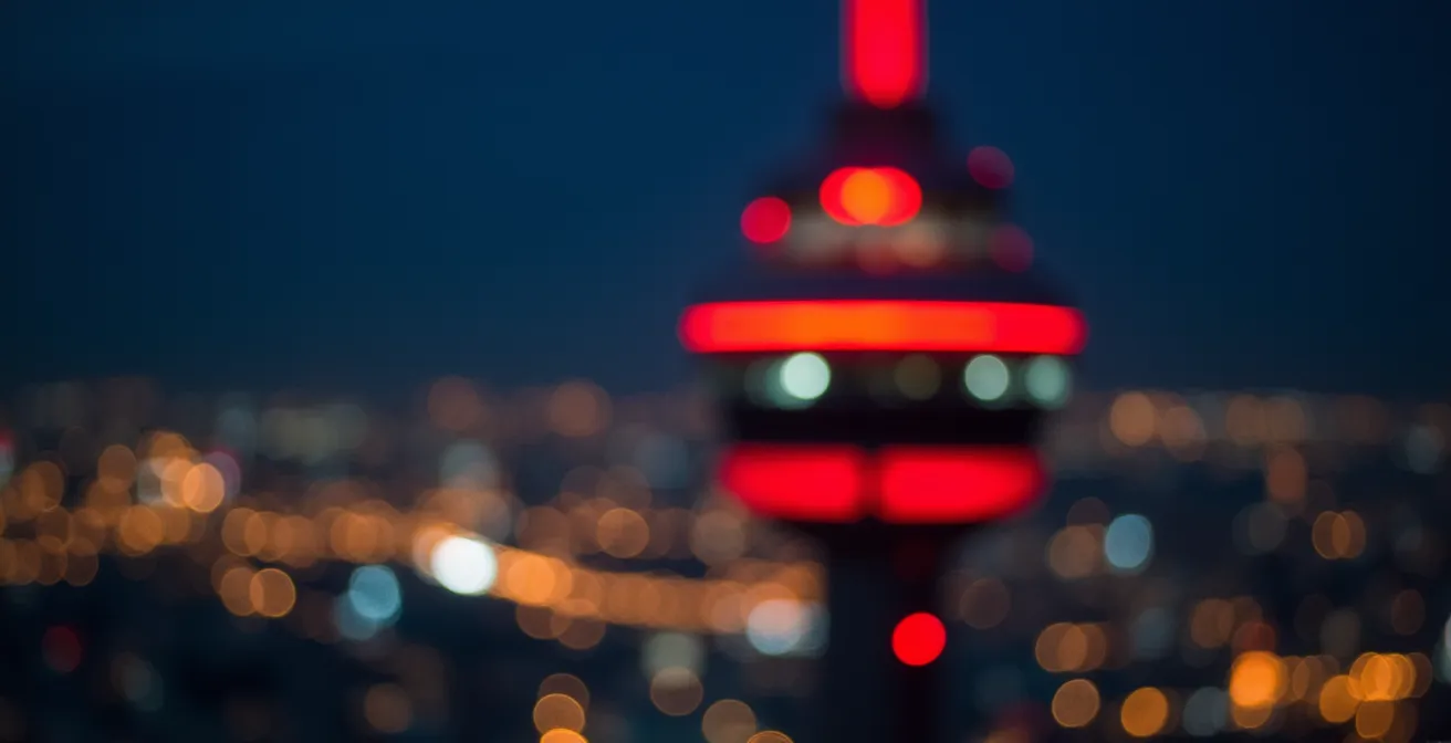 Extreme close-up of CN Tower antenna lights creating bokeh patterns at night